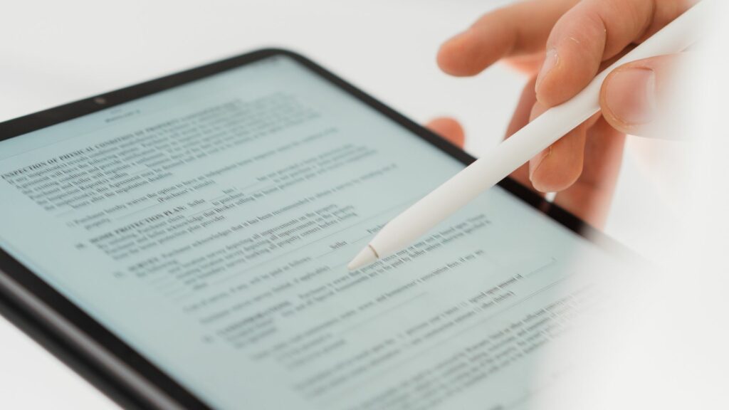 Immagine di un tablet tenuto da una mano con uno stilo. Lo schermo mostra un documento con testo e tabelle, presumibilmente un rapporto o un modulo sviluppato con l'intelligenza artificiale.